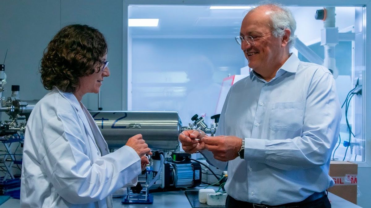 Researchers Teresa Puig and Xavier Obradors at a lab, holding a long thin superconductor.